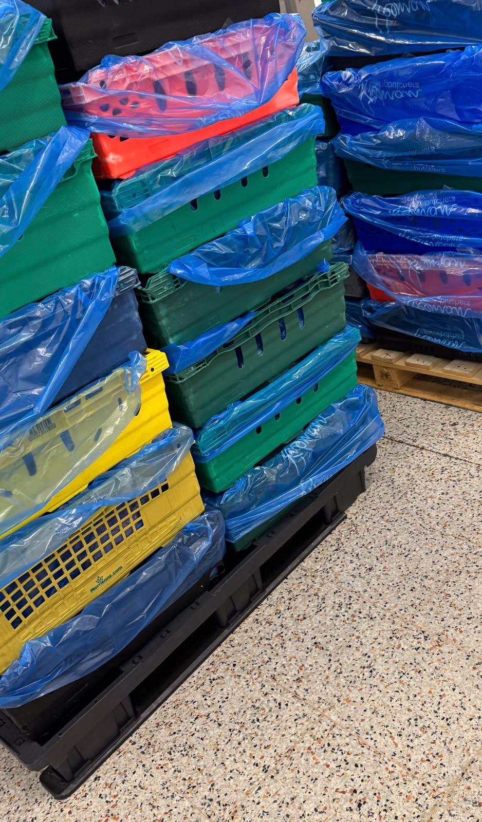 Colour-coded delivery crates lined and stacked on a pallet, ready for the day's rounds