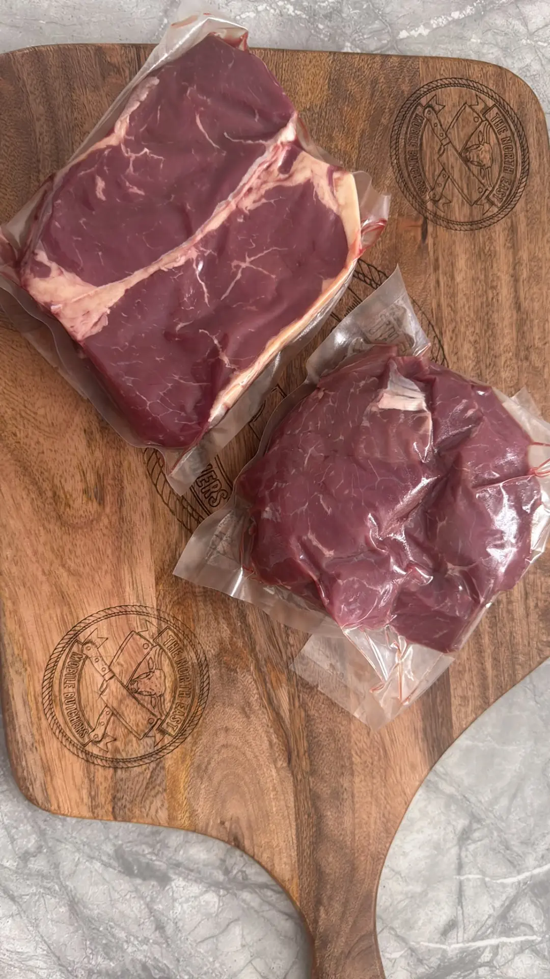 Vacuum-packed butcher-prepared steaks on an engraved North East Mobile Butchers board